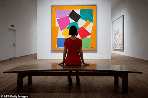 A girl sits to look at an abstract painting