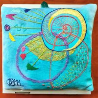Hand embroidery on painted turquoise linen expressing the joy of life