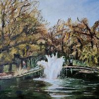 A Victorian pond with a central fountain set in parkland. The water forms spray and white ripples in the water. Autumn trees in the background. 