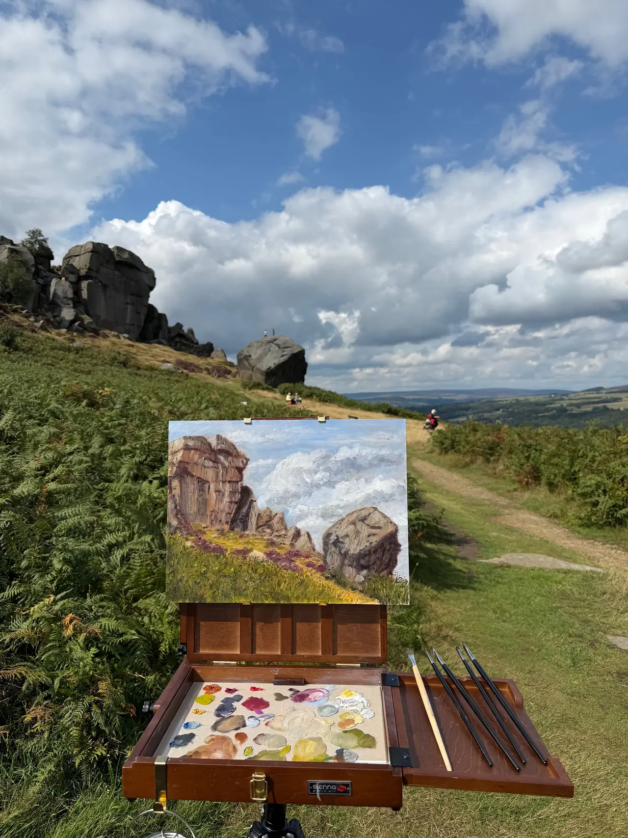 Plein-air oil painting on an easel overlooking the Cow and Calf rocks and moorland at Ilkley, West Yorkshire.
