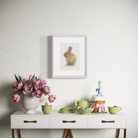 Coloured pencil drawing by Katrina Thompson of little easter bunny above a table set with flowers and easter decorations 
