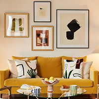 A living room with sofa and 4 framed artworks on the wall