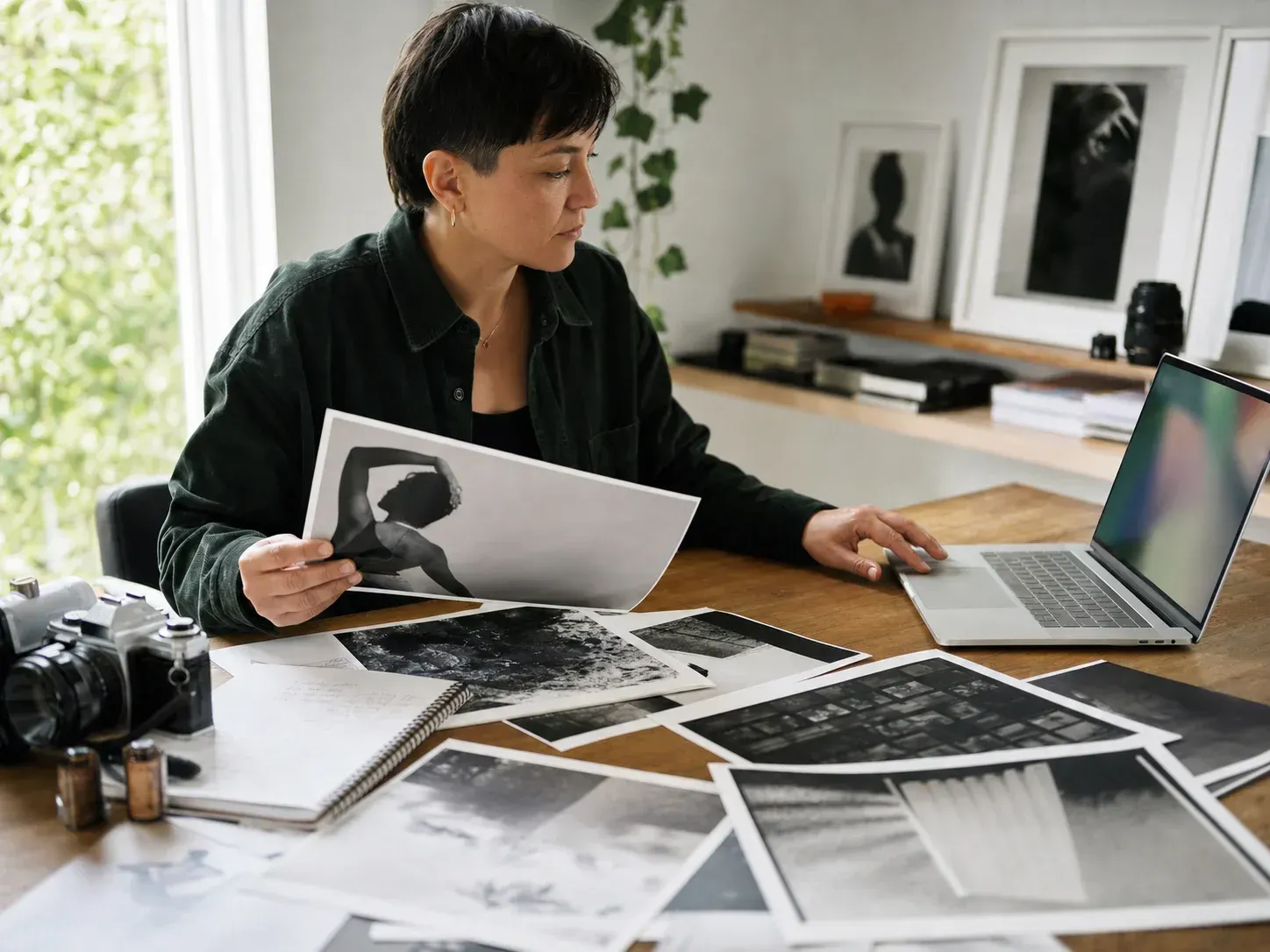 Photographer selecting prints beside a laptop in a studio