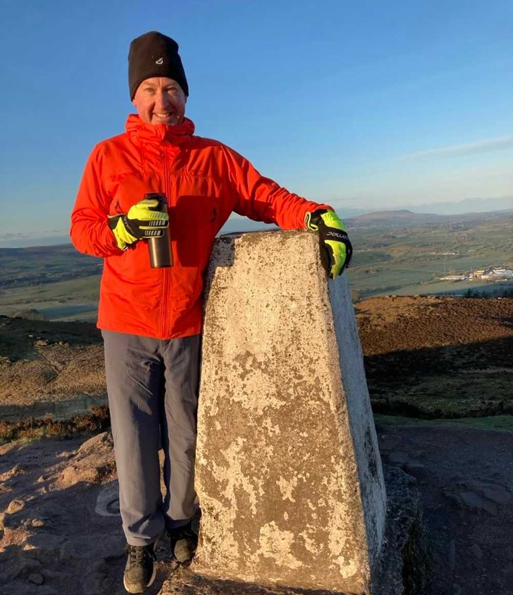 Jonathan Little is posing on top of Sharpaw Mountain in Skipton holding a flask of coffee